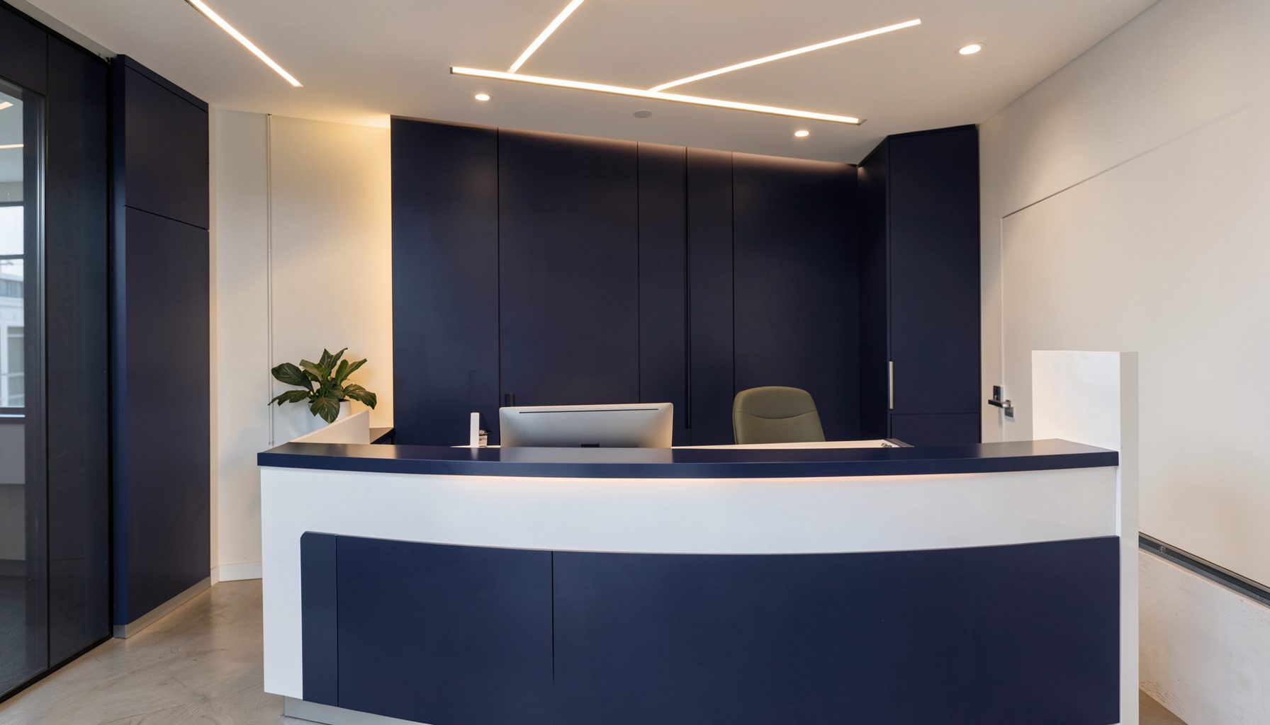 A clean, modern office reception desk with warm ambient lighting, navy and white tones, and a calm professional atmosphere
